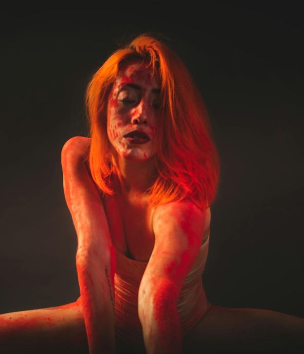 Young woman performing dynamic stretching in a modern dark studio.
